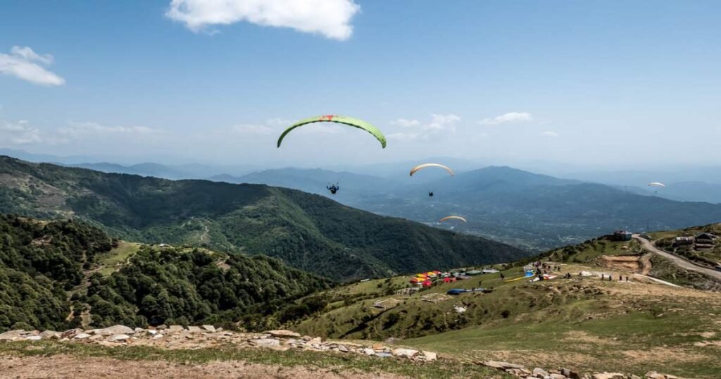 Paragliders soaring over the Dhauladhar range in Bir-Billing, celebrated as India's paragliding capital.