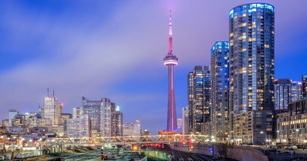 The iconic CN Tower towering over Toronto's skyline against a clear blue sky.