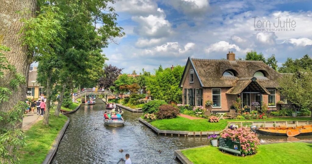 A scenic canal in Giethoorn, lined with charming thatched-roof houses and lush greenery.