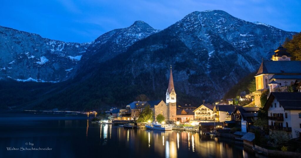 The charming village of Hallstatt is reflected in the crystal-clear waters of Hallstätter See, with the Alps in the background.