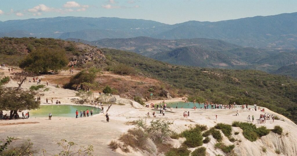 Crystal-clear mineral pools perched at the edge of a cliff with panoramic mountain views.