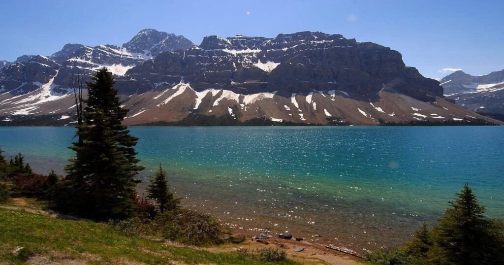 “A canoe gliding across the crystal-clear waters of Maligne Lake surrounded by snow-capped mountains.”