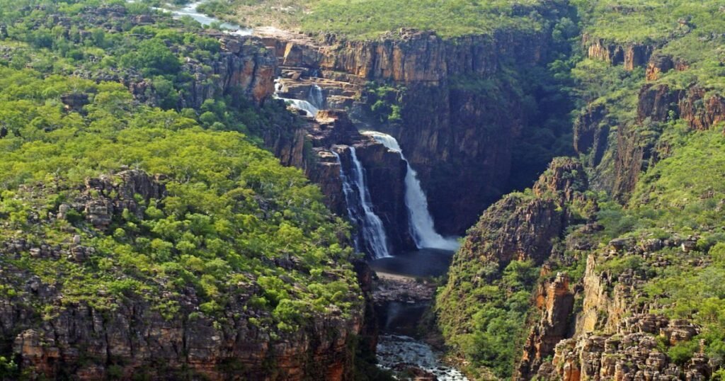 The dramatic Jim Jim Falls cascades into a deep pool, surrounded by lush greenery in Kakadu National Park.