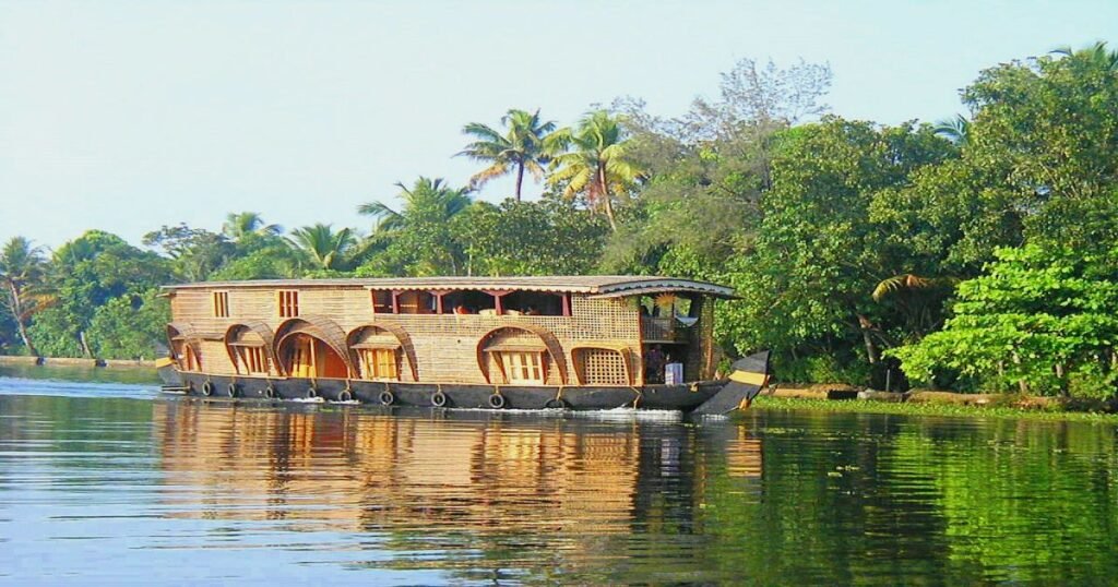 A houseboat gliding through the tranquil Kerala backwaters with lush greenery on either side.