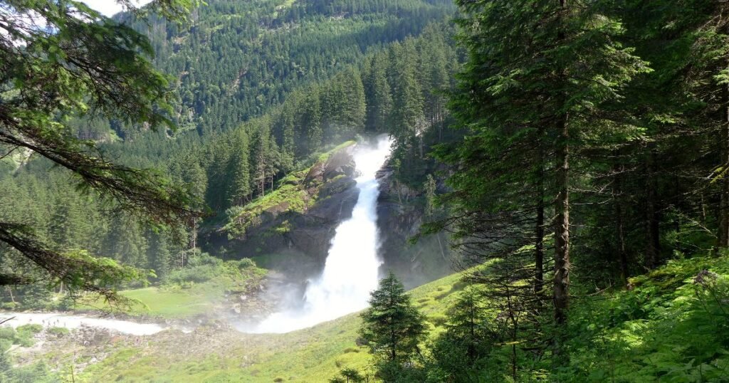 “A breathtaking view of Krimml Waterfalls cascading down rocky cliffs amidst lush green forests.”