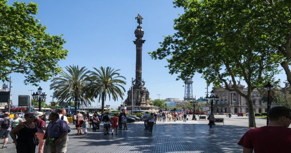 A bustling La Rambla street filled with tourists, cafés, and flower stalls under tree-lined walkways.