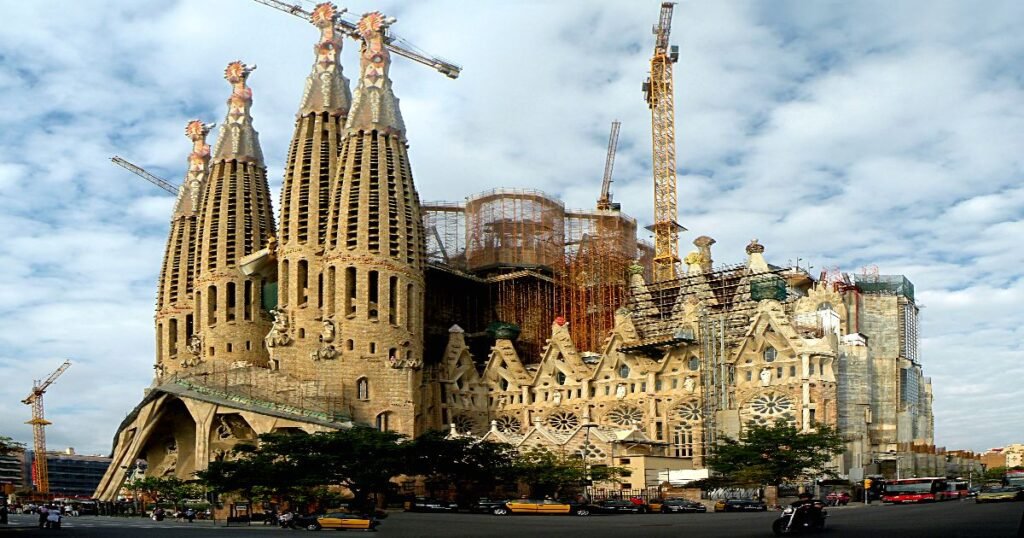 La Sagrada Familia basilica with its iconic spires reaching into the sky under a bright blue sky.