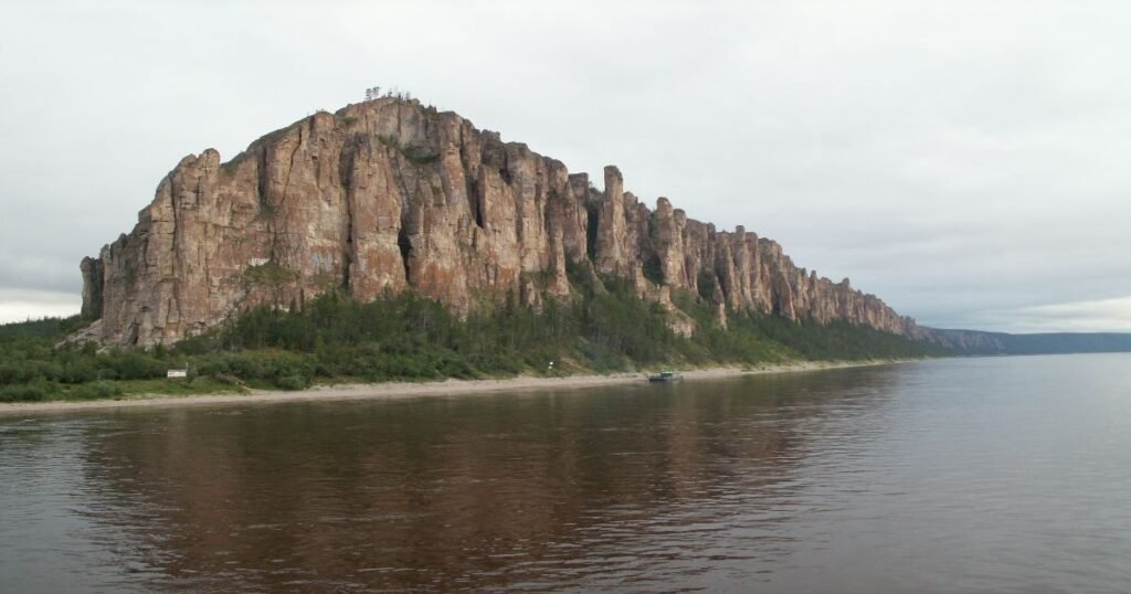 “The dramatic Lena Pillars rising majestically along the banks of the Lena River, framed by dense forests.”