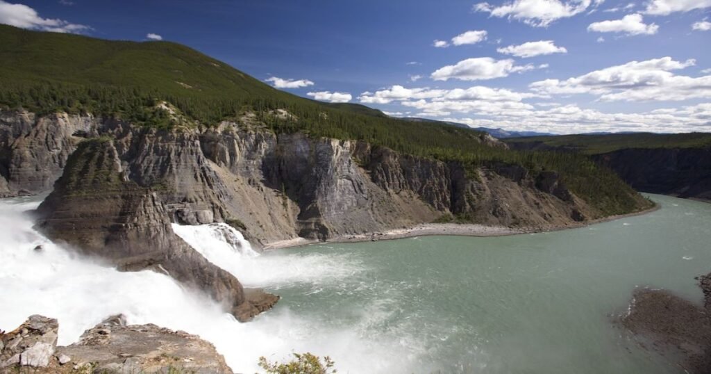 “A breathtaking aerial view of Virginia Falls in Nahanni National Park, with mist rising from the cascading water.”