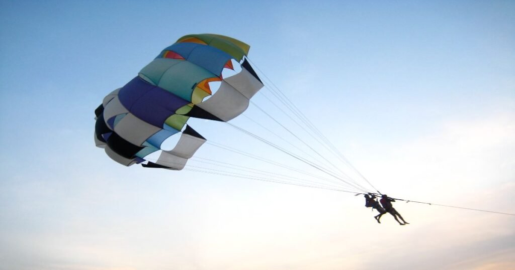 Thrill-seekers parasailing above the beautiful beaches of Goa, known for its vibrant nightlife and adventure sports.