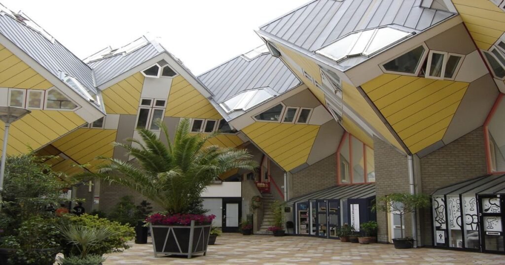 The iconic yellow and tilted Cube Houses in Rotterdam, set against a blue sky, showcasing their modern architectural style.