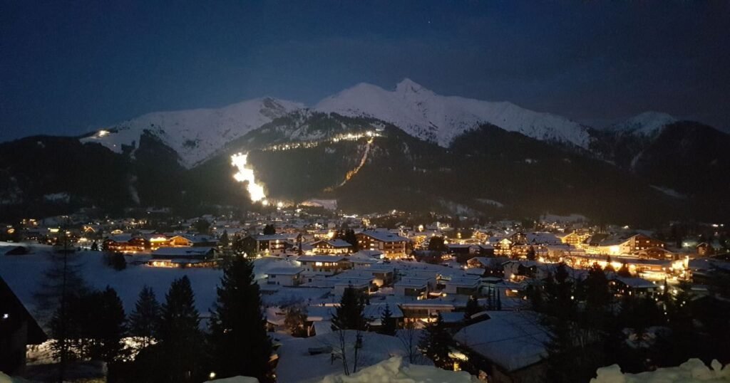 The charming alpine village of Seefeld is covered in snow, surrounded by towering peaks and evergreen trees.