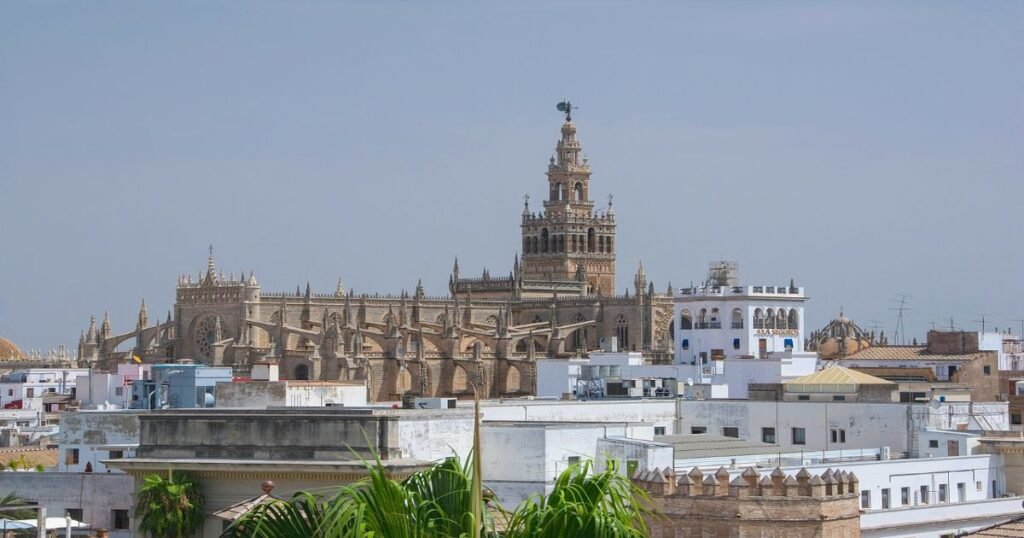 Seville Cathedral’s grand Gothic architecture and the towering La Giralda against a bright blue sky.