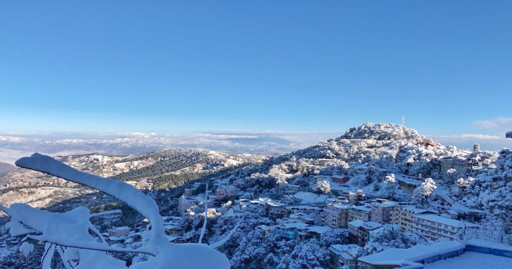 Panoramic view of Shimla with snow-capped mountains in the background."