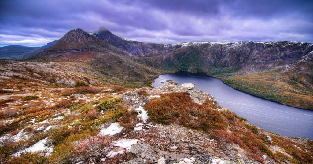  Majestic Cradle Mountain reflecting in the still waters of Dove Lake with surrounding greenery.