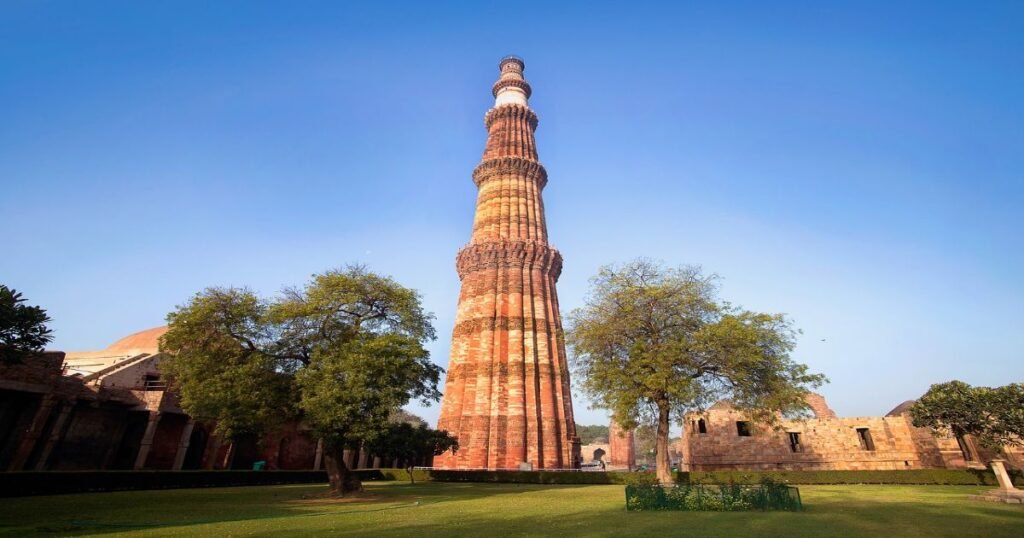 The Qutub Minar, a tall red sandstone tower with intricate carvings and inscriptions.