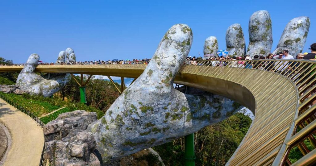 "The famous Golden Bridge at Ba Na Hills, supported by two massive stone hands, surrounded by mist and greenery in central Vietnam."