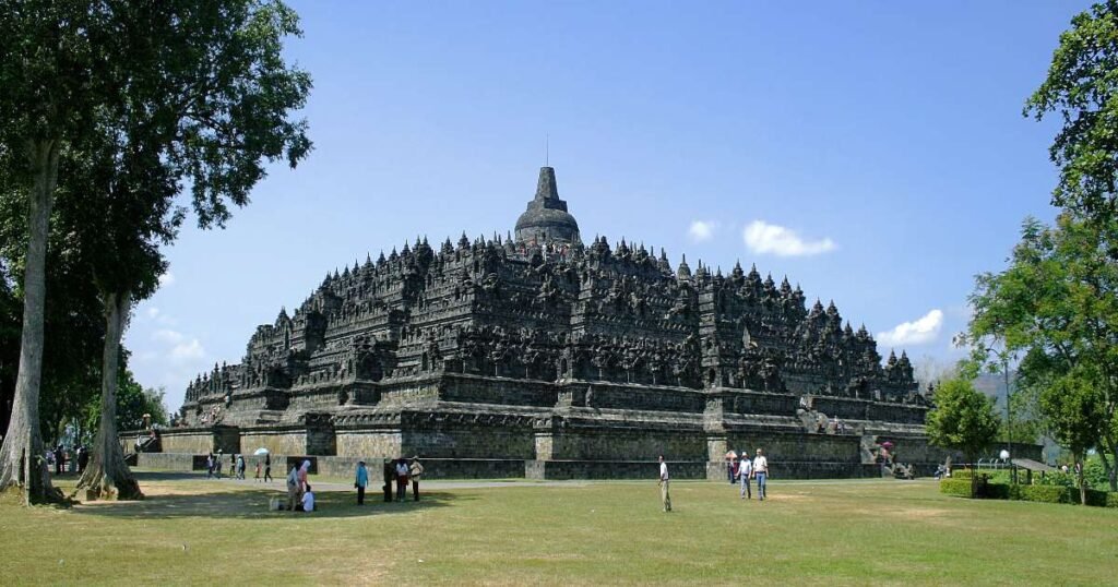 "Borobudur Temple at sunrise, with mist surrounding its ancient stupas."