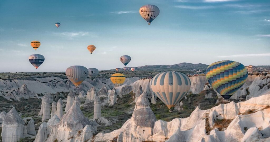 "Hot air balloons floating over the surreal landscape of Cappadocia, with its famous fairy chimneys and rock formations."