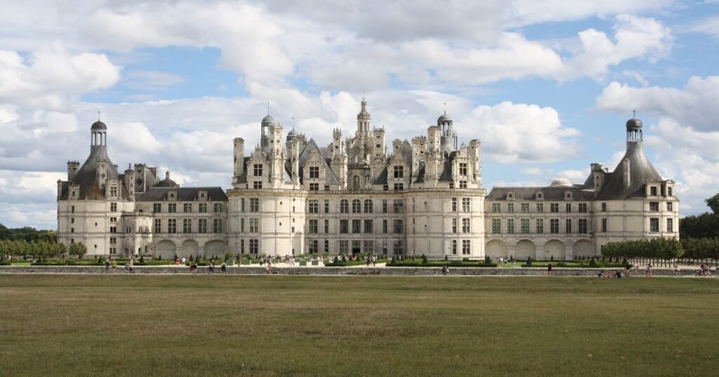 The grand façade of Château de Chambord, surrounded by lush gardens and reflecting pools.