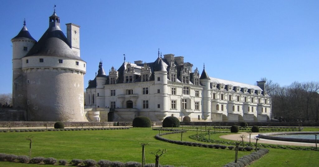 The Château de Chenonceau reflecting in the waters of the Cher River, surrounded by lush gardens.