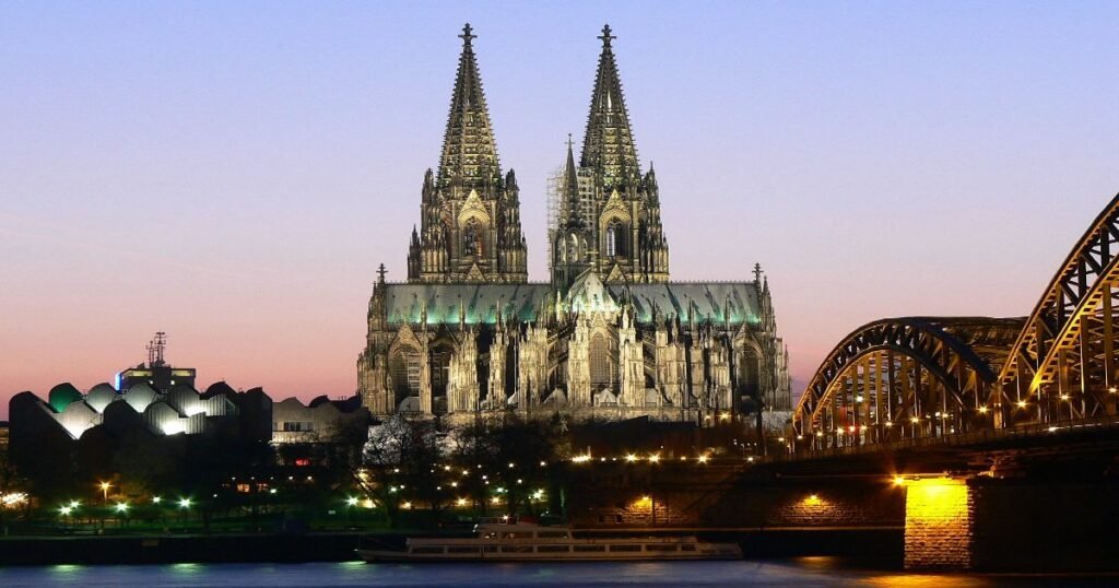 The iconic Cologne Cathedral with its towering twin spires against a blue sky, symbolizing Gothic grandeur."