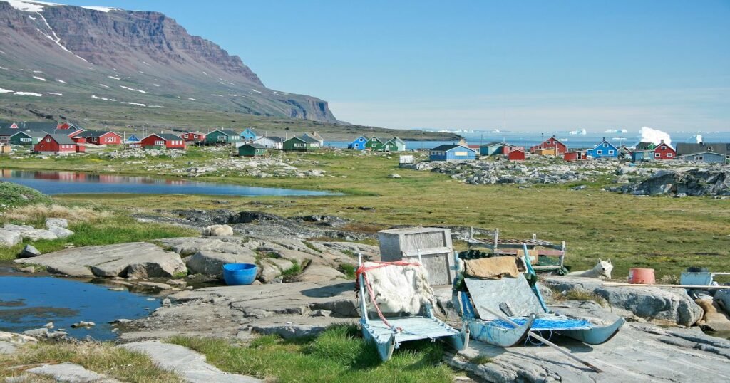 “Volcanic cliffs of Disko Island rising above colorful tundra and the deep-blue waters of Disko Bay.”