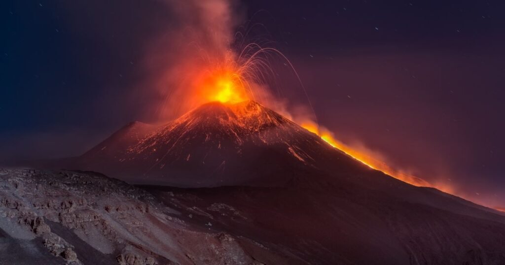Mount Etna, with plumes of smoke and lava rising from the crater.