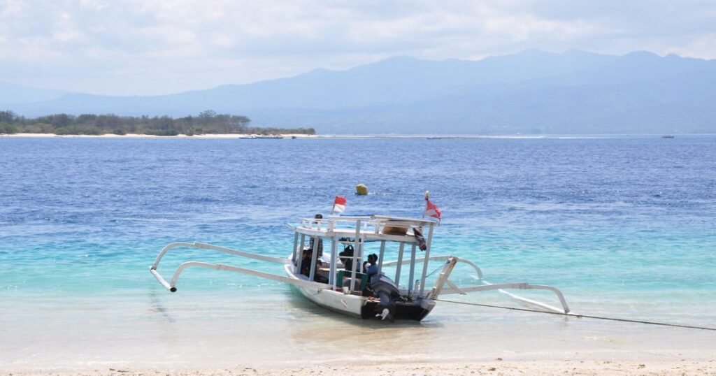 "Crystal-clear waters and white sandy beaches on the Gili Islands with a backdrop of palm trees."