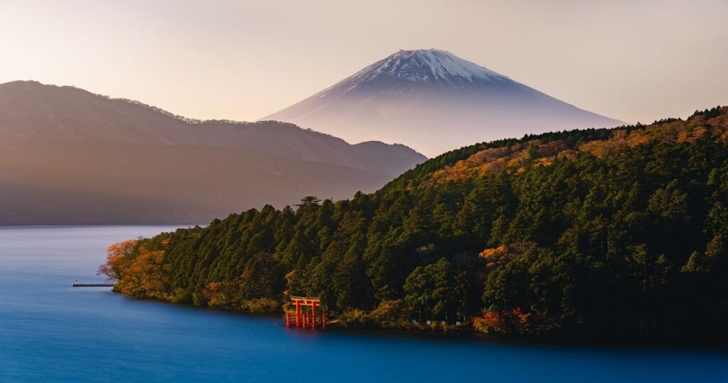 "Panoramic view of Lake Ashi, with Mount Fuji visible in the distance and a torii gate standing by the lake's shore."