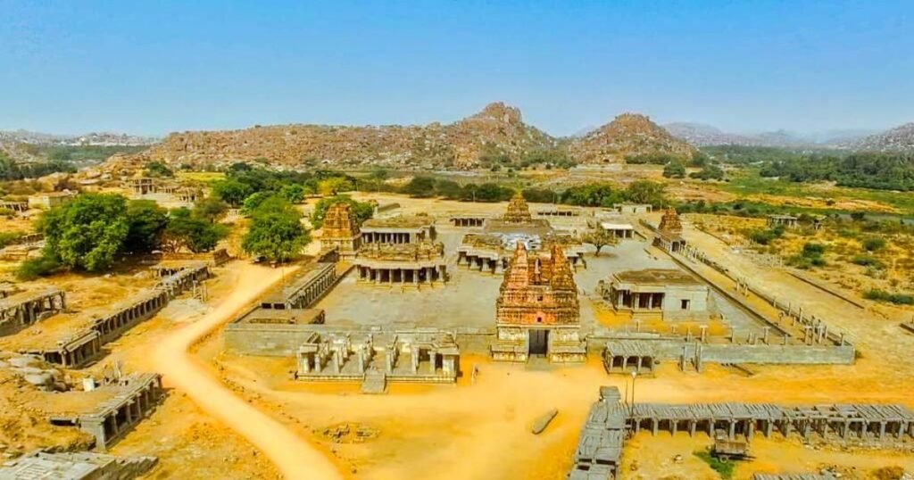 “Ruins of Hampi, showcasing ancient stone-carved temples amidst a rugged terrain.”