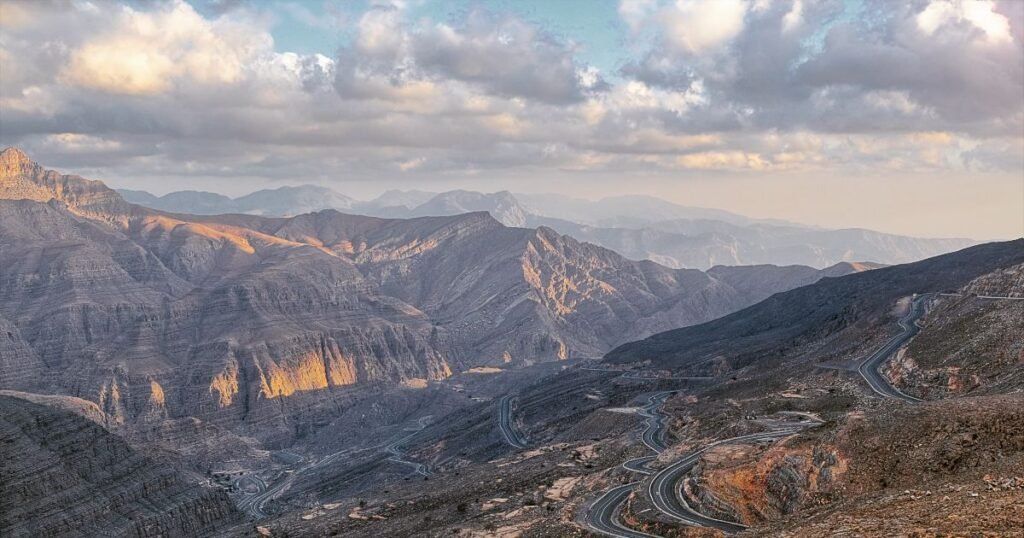 "Scenic view from the top of Jebel Jais, the highest peak in the UAE, with winding roads below."