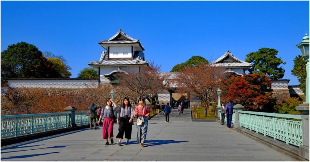 "Kanazawa Castle with its towering stone walls and lush greenery, adjacent to the serene Kenrokuen Garden."