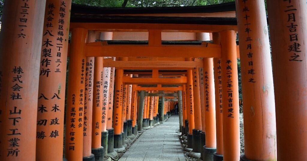 "Rows of bright red torii gates winding up the path to Fushimi Inari Shrine."