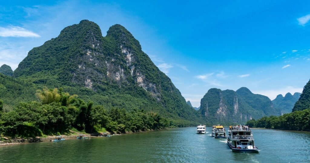 "Modern  boats on the calm waters of the Li River, surrounded by towering karst peaks."