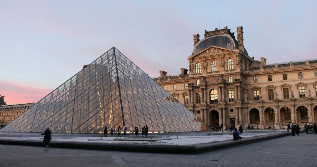 The Louvre Museum with its iconic glass pyramid reflecting the morning sunlight.