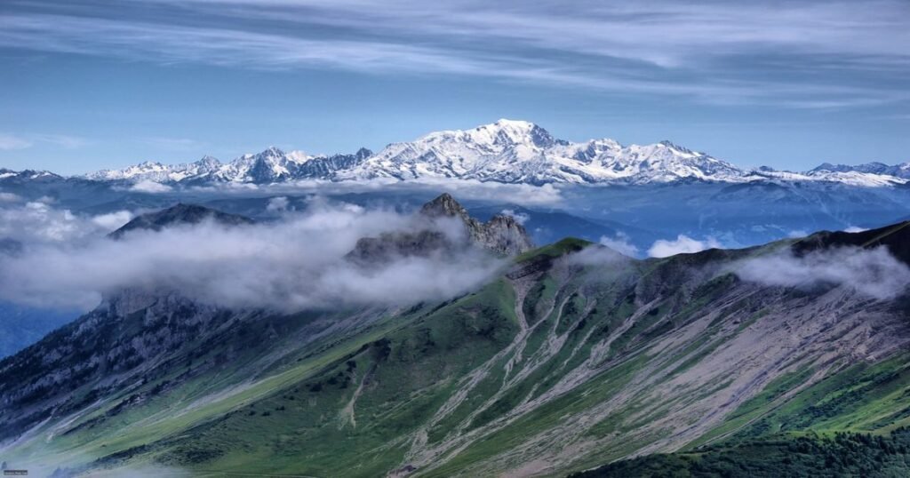 The snow-capped peak of Mont Blanc towering above the green valleys of the French Alps.