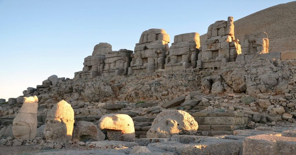 "Colossal stone heads of ancient gods and kings on Mount Nemrut, Turkey, illuminated by the setting sun."