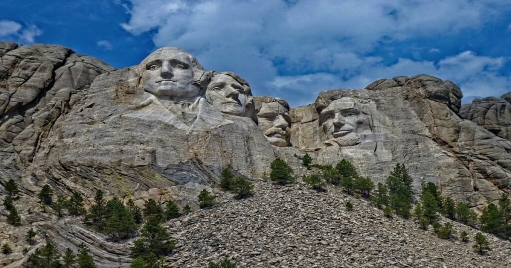 “Mount Rushmore’s detailed sculptures of U.S. presidents’ faces carved into a massive granite mountain.”