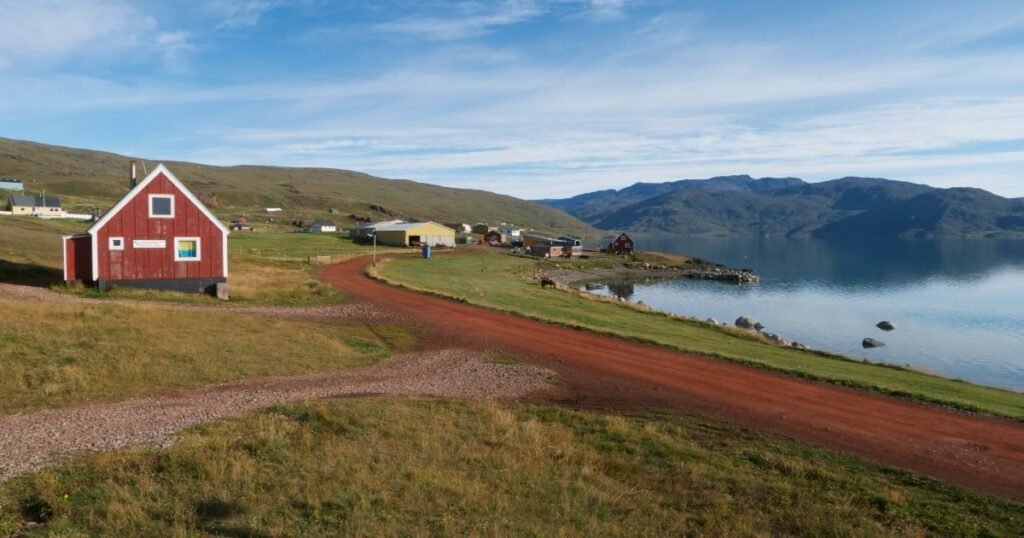 “The green fields of the Kujataa UNESCO World Heritage Site, dotted with Norse ruins and surrounded by dramatic mountains.”