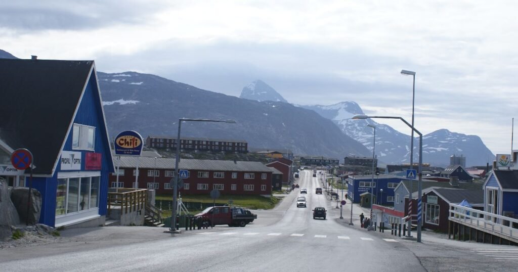 “Nuuk’s vibrant harbor with colorful houses and snow-capped mountains in the background.”