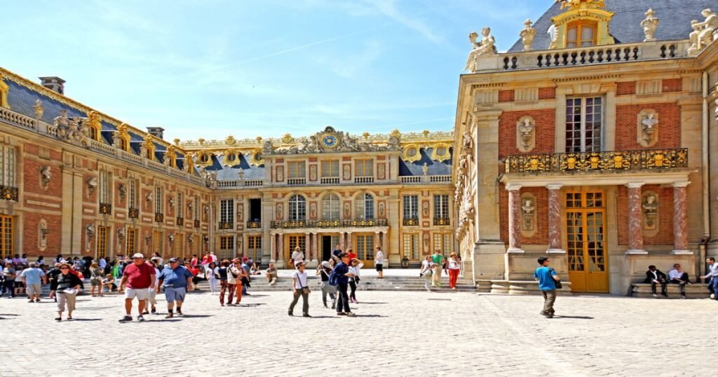 The opulent façade of the Palace of Versailles with its manicured gardens and fountains.