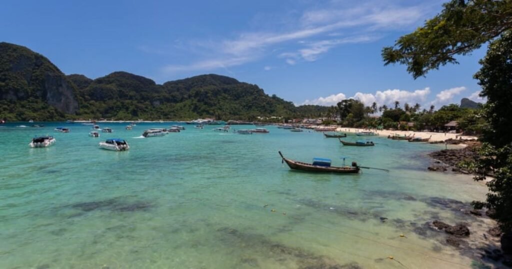 “Pristine beach in Phuket with white sand, turquoise water, and palm trees under a clear blue sky.”