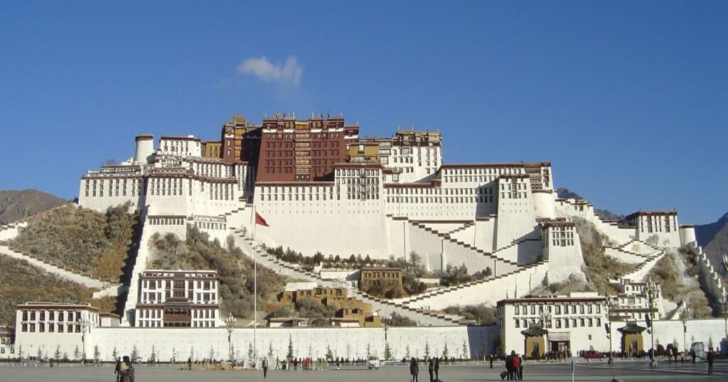 "The Potala Palace, a towering white and red structure perched on a hilltop overlooking Lhasa."