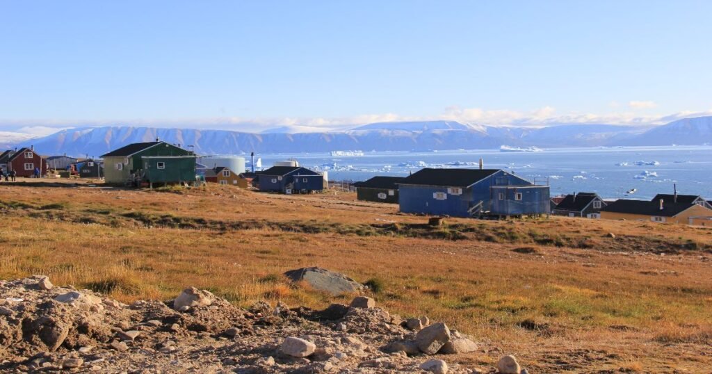 “The remote town of Qaanaaq, surrounded by icy landscapes and illuminated by the soft glow of the Arctic midnight sun.”