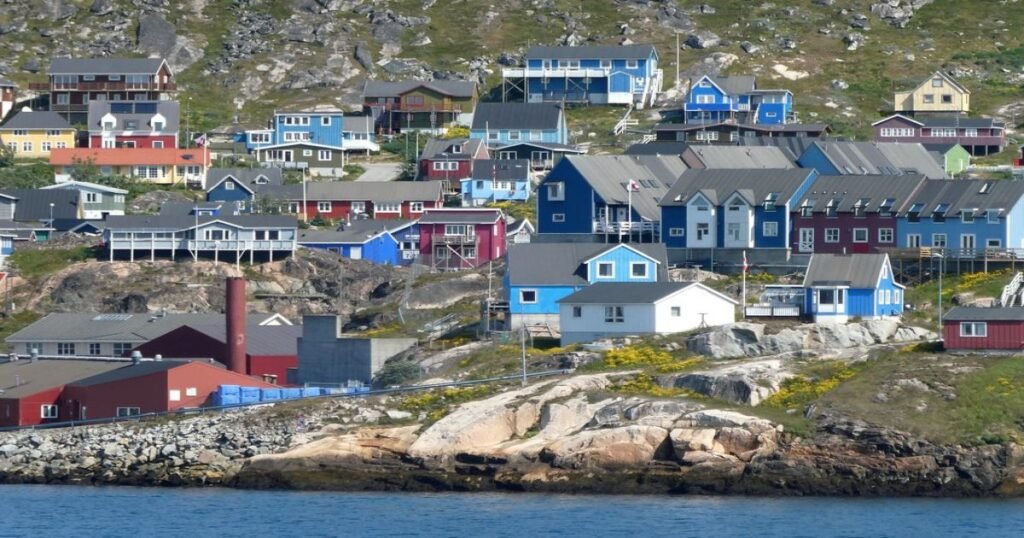 “The colorful houses of Qaqortoq set against a backdrop of rolling hills and deep-blue waters.”