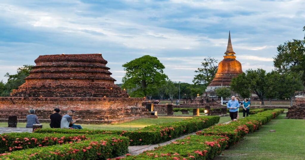 “Ancient ruins of Sukhothai Historical Park, with towering Buddha statues and lotus-bud chedis.”