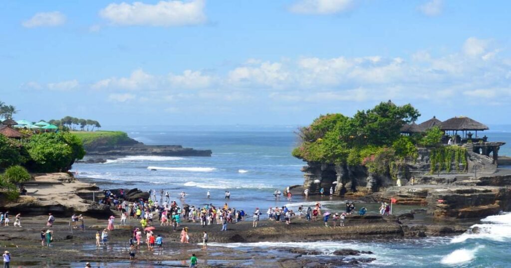 "Tanah Lot Temple at sunset, surrounded by ocean waves."