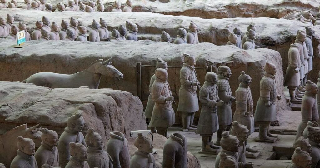 "Rows of life-sized Terracotta warriors, each with unique facial features, stand in formation."