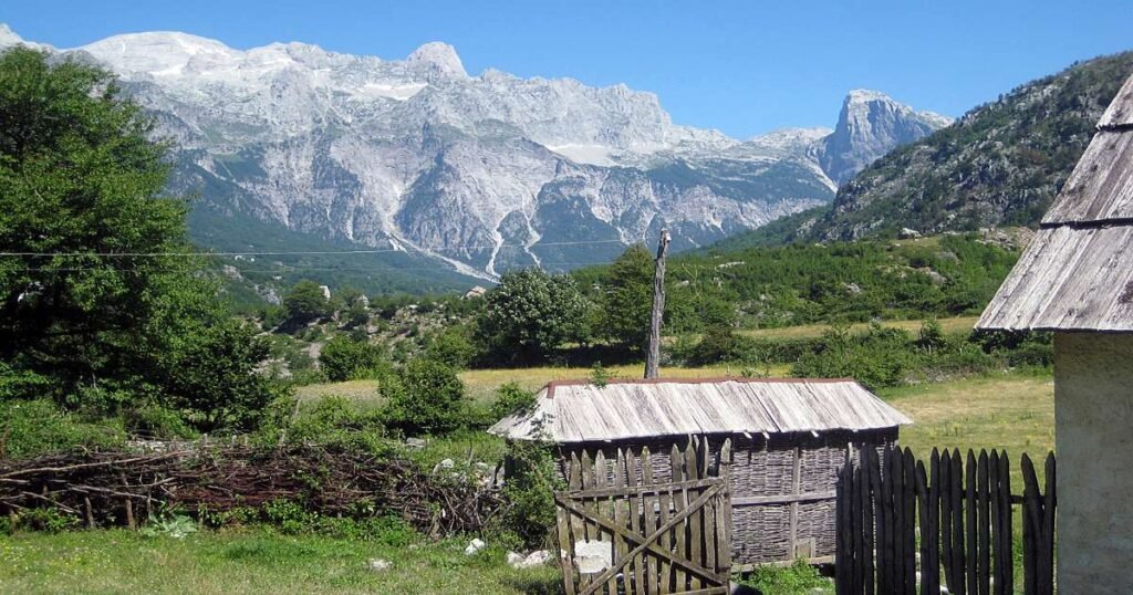 "Majestic mountains and a traditional stone house in Theth National Park."